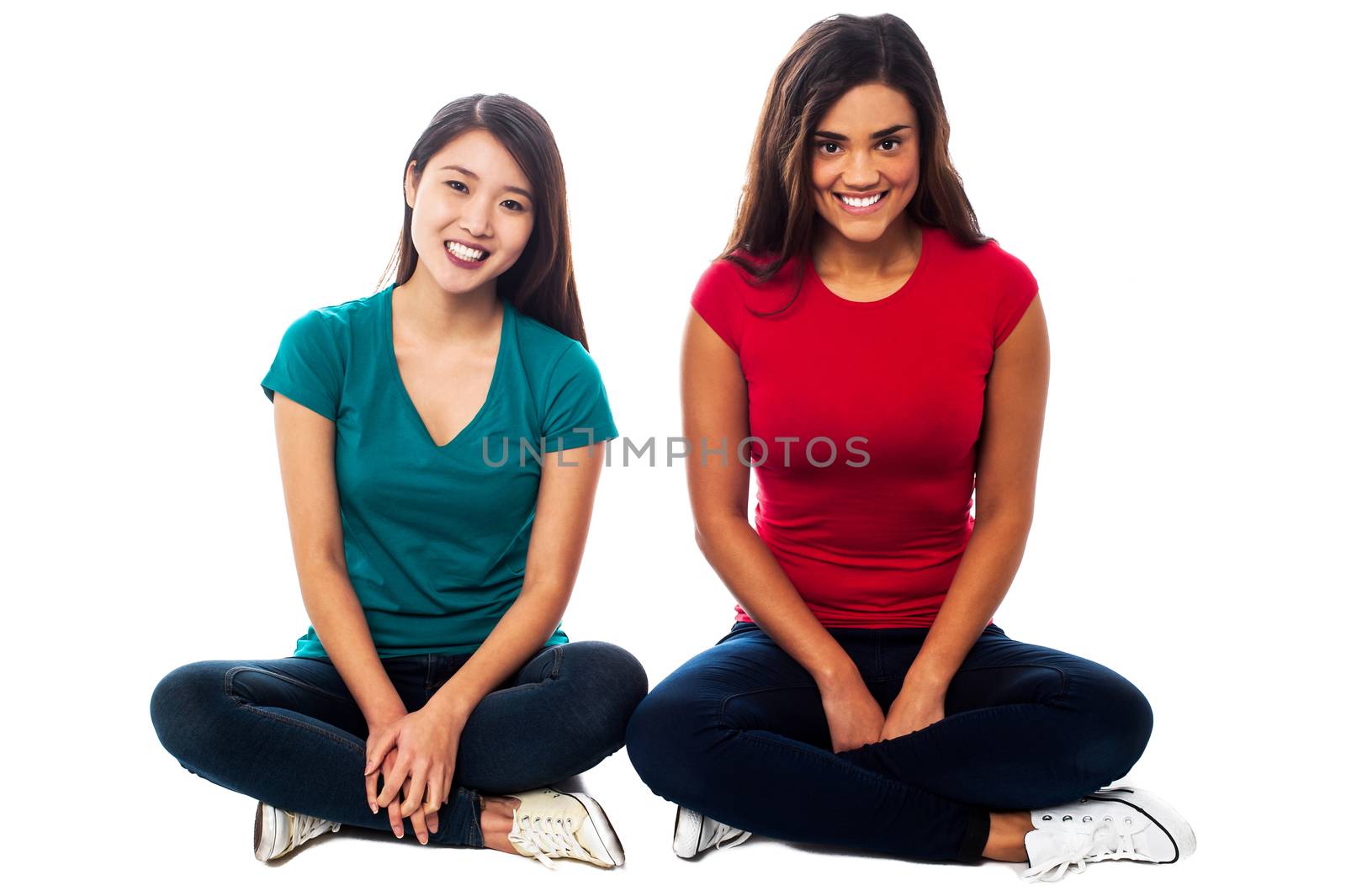 Two young girls sitting on the floor, legs crossed