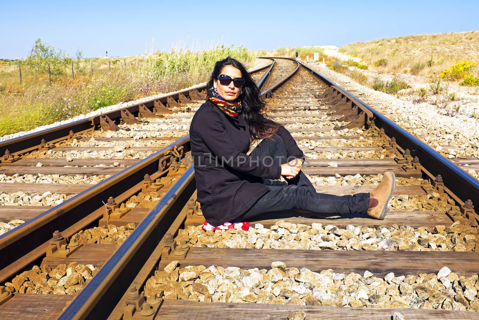 Young beautiful woman sitting on a railroad track by devy