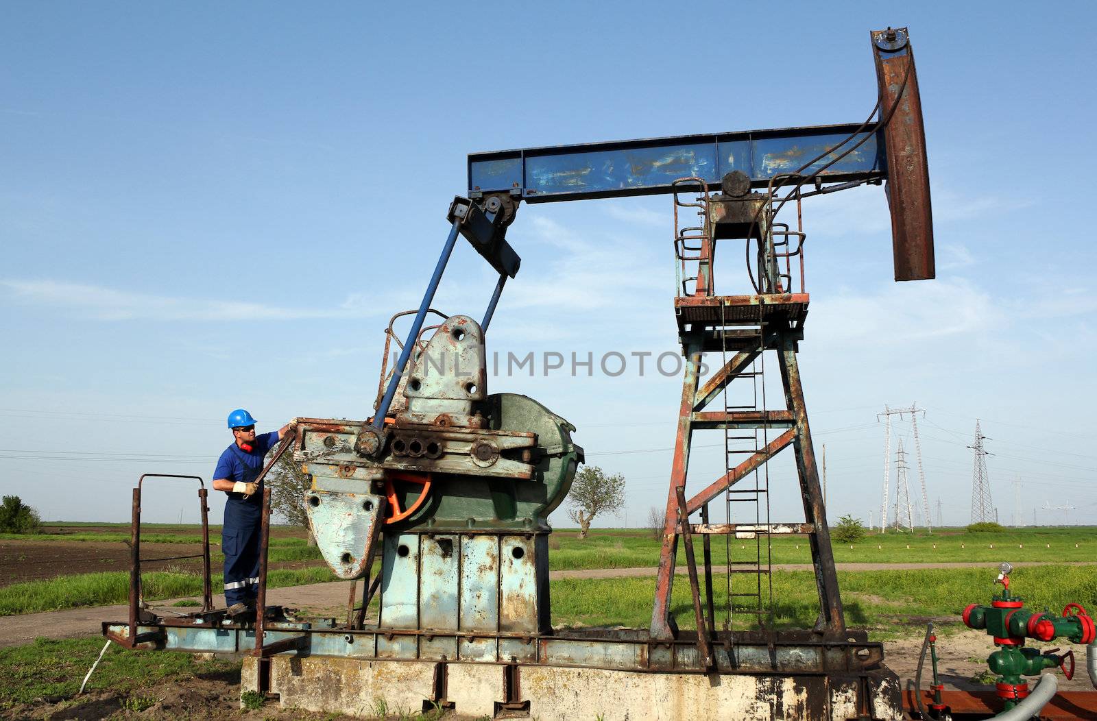 oil worker working on pump jack by goce