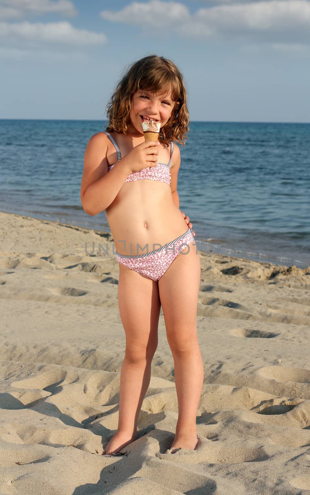 happy little girl eat ice cream on beach
