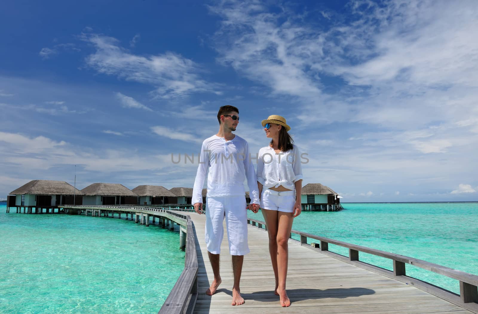 Couple on a tropical beach jetty at Maldives