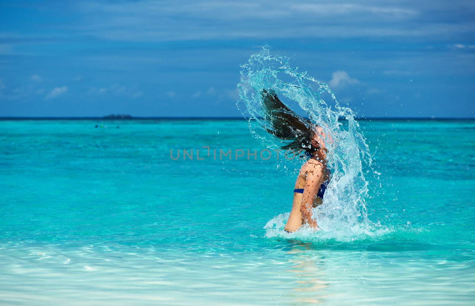 Woman splashing water with her hair in the ocean