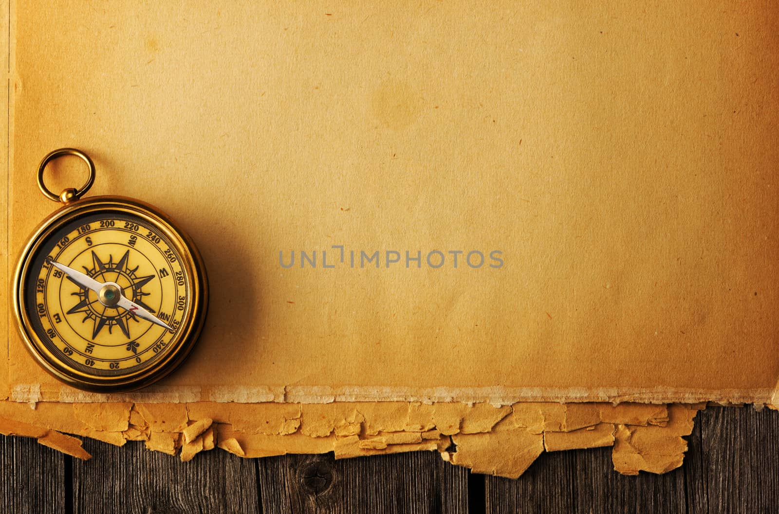 Antique brass compass over old paper background