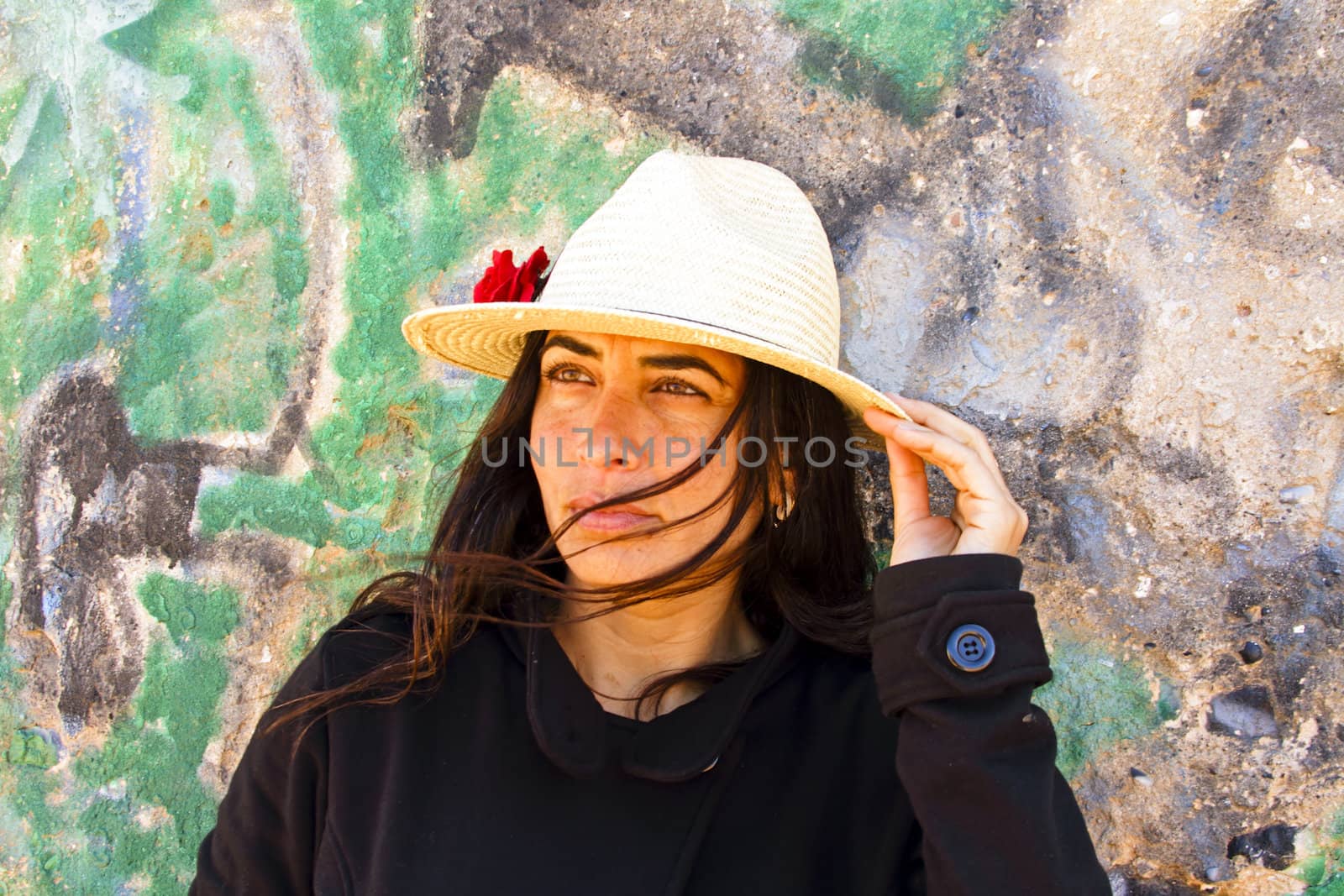 Beautiful woman in black in front of a graffiti brick wall