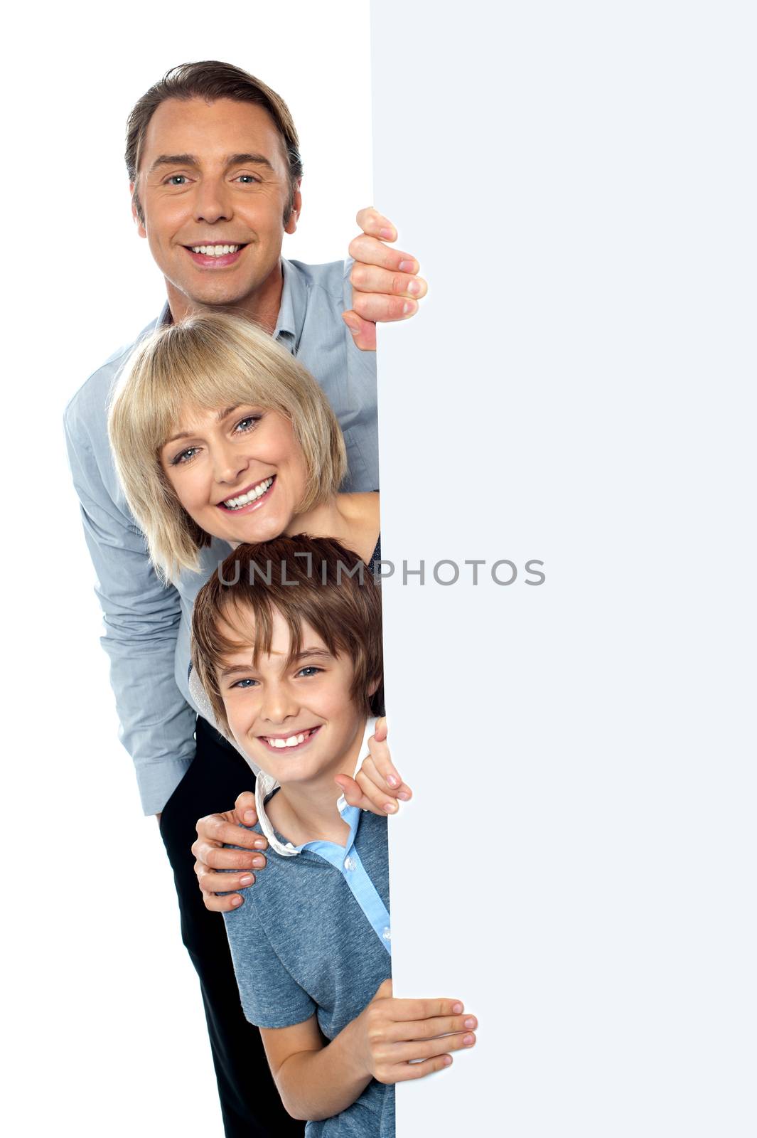 Family posing from behind blank white ad board