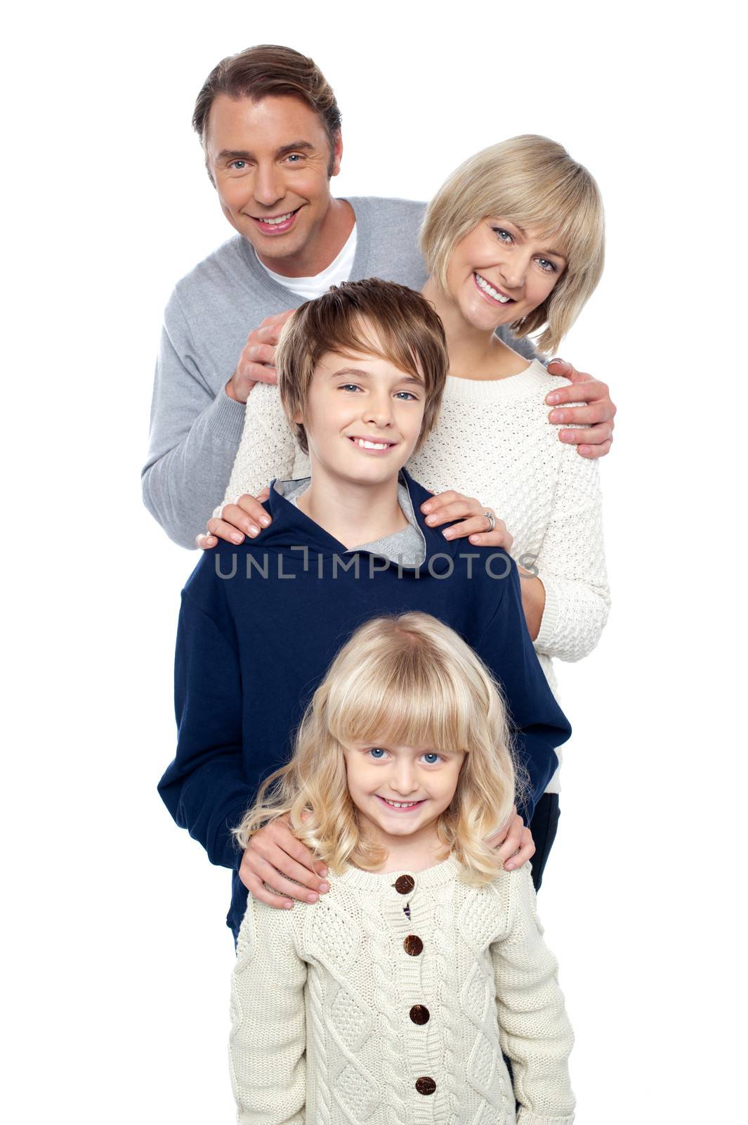 Family of four posing in a row by stockyimages