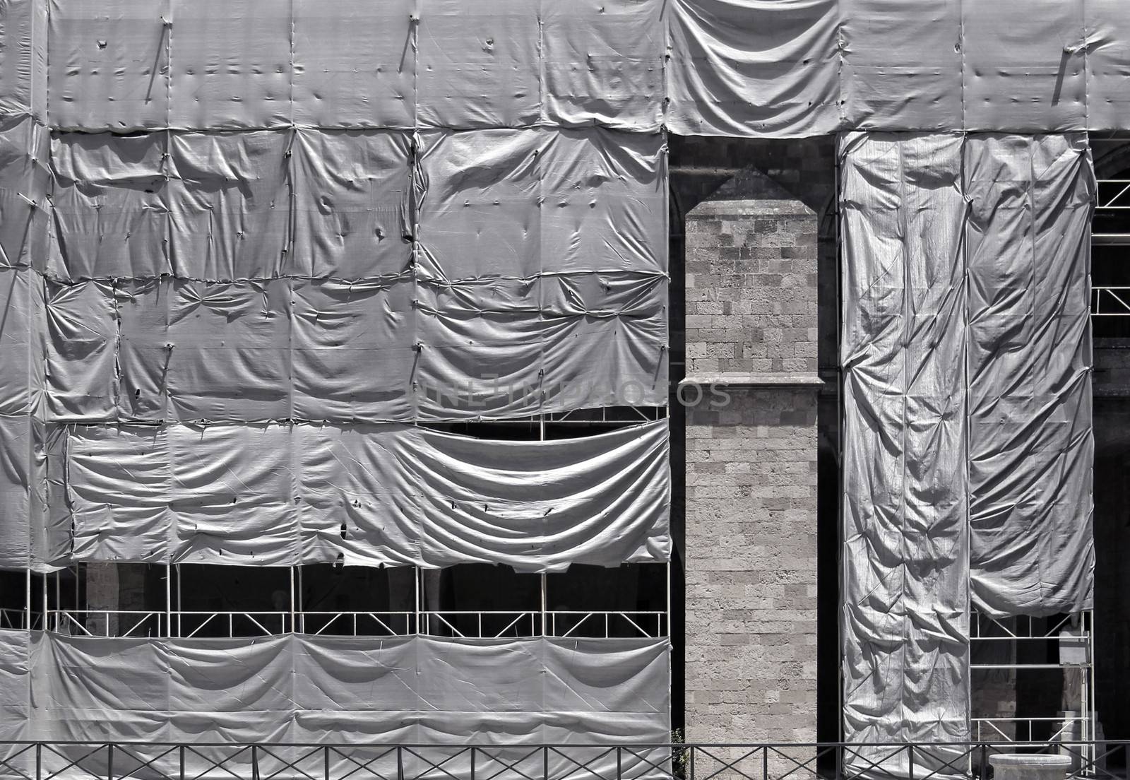 Building under conctruction covered with wrinkled tarpaulin canvas