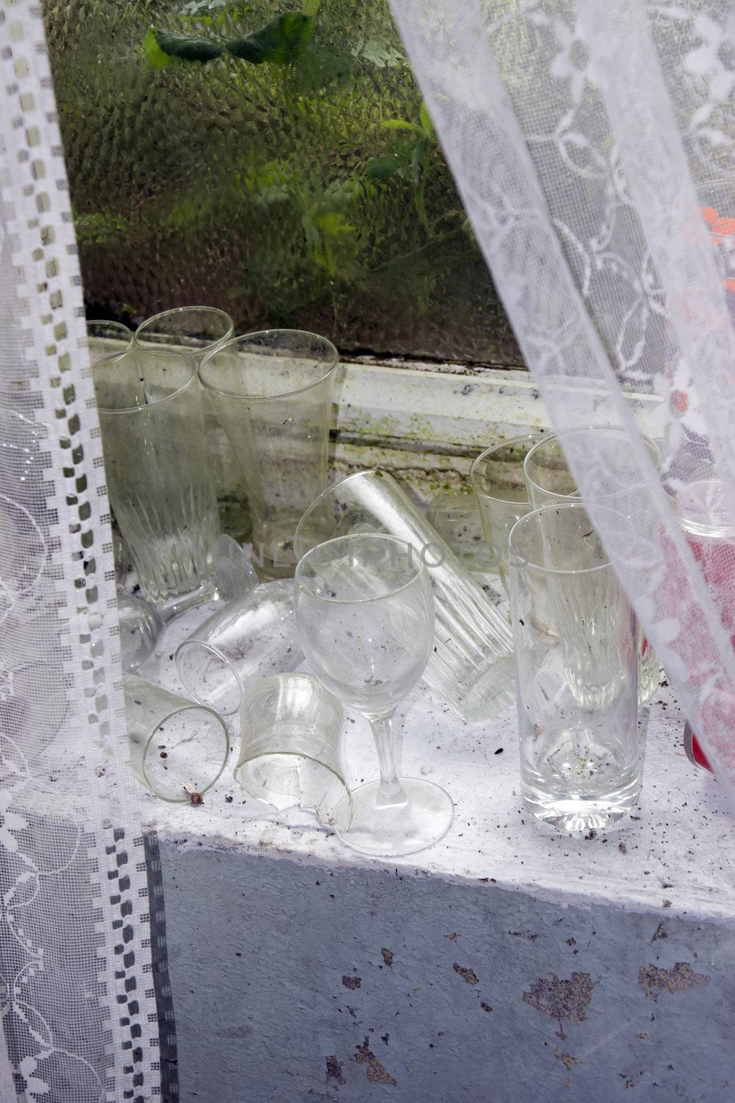 decaying old room window with a windowsill full of dirty glasses