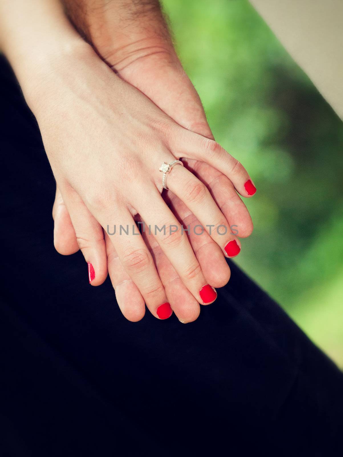 Close up picture of holding hands and engagement ring