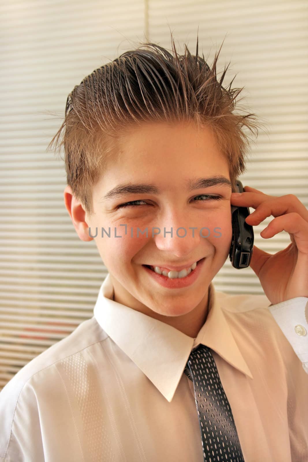 busines style boy in the white shirt stand near jalousie and talking by phone