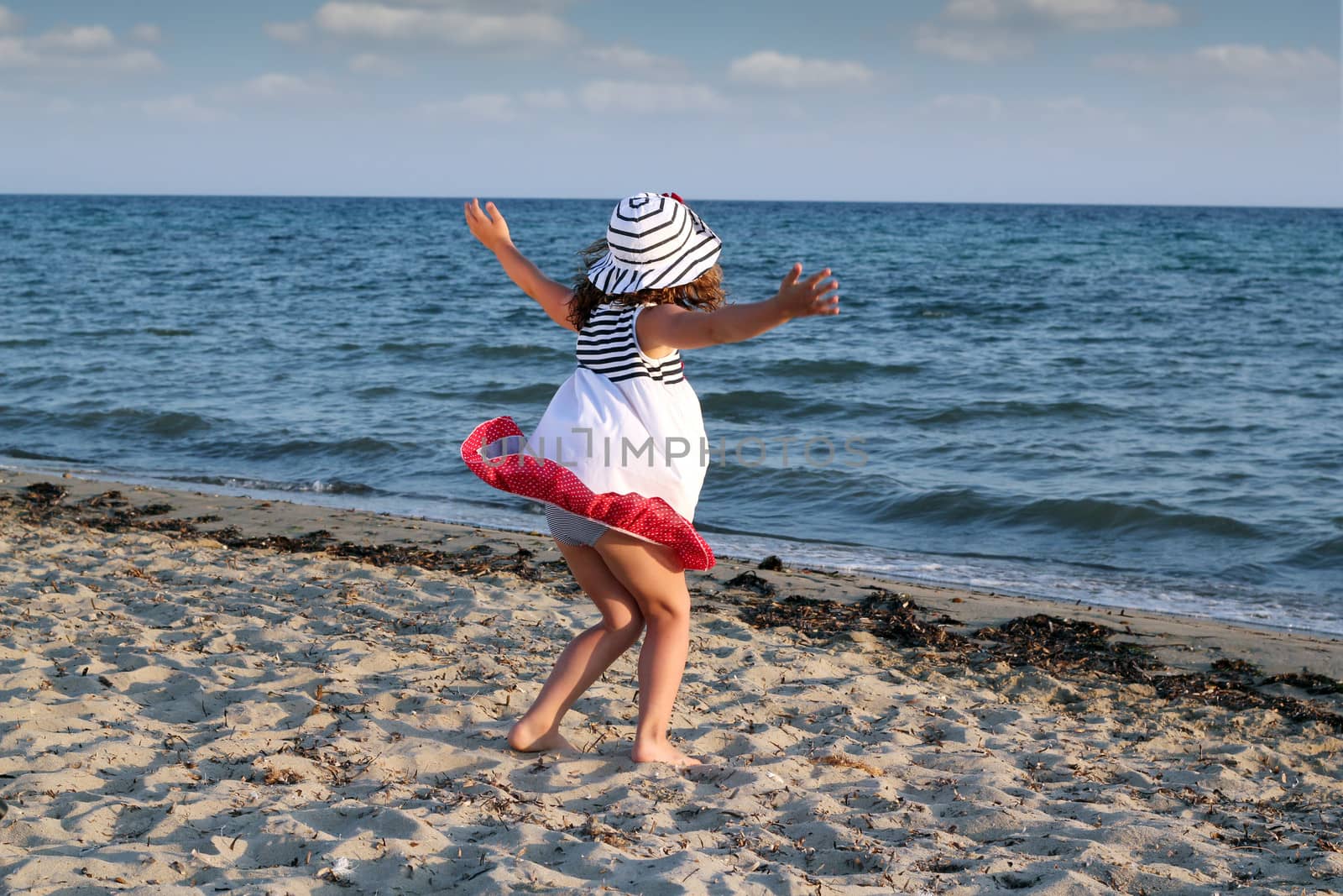little girl running on beach by goce