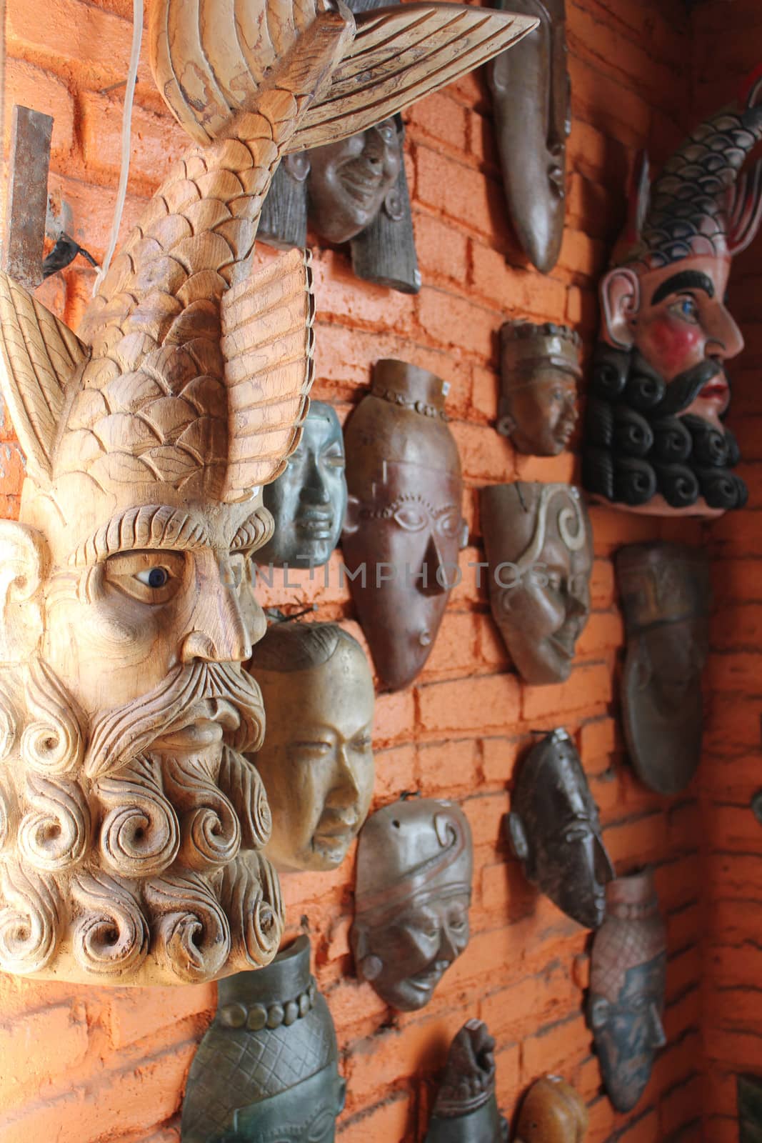Carved and painted wooden Mayan masks on display (and for sale) on a brick wall in an indoor market in Mazatlan, Mexico