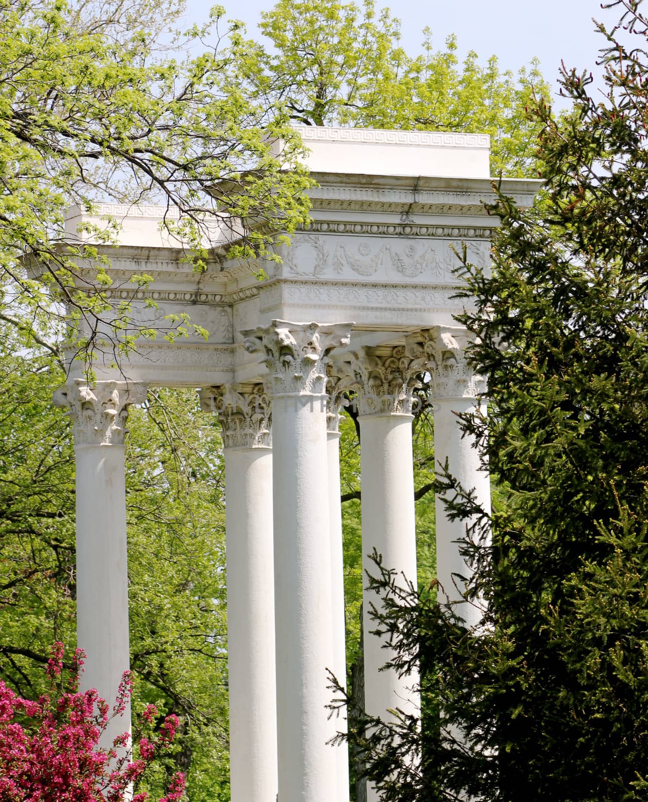 An aged and weathered stone monument featuring Corinthian columns, surrounded by trees, at Graceland Cemetery, Chicago, Illinois, USA