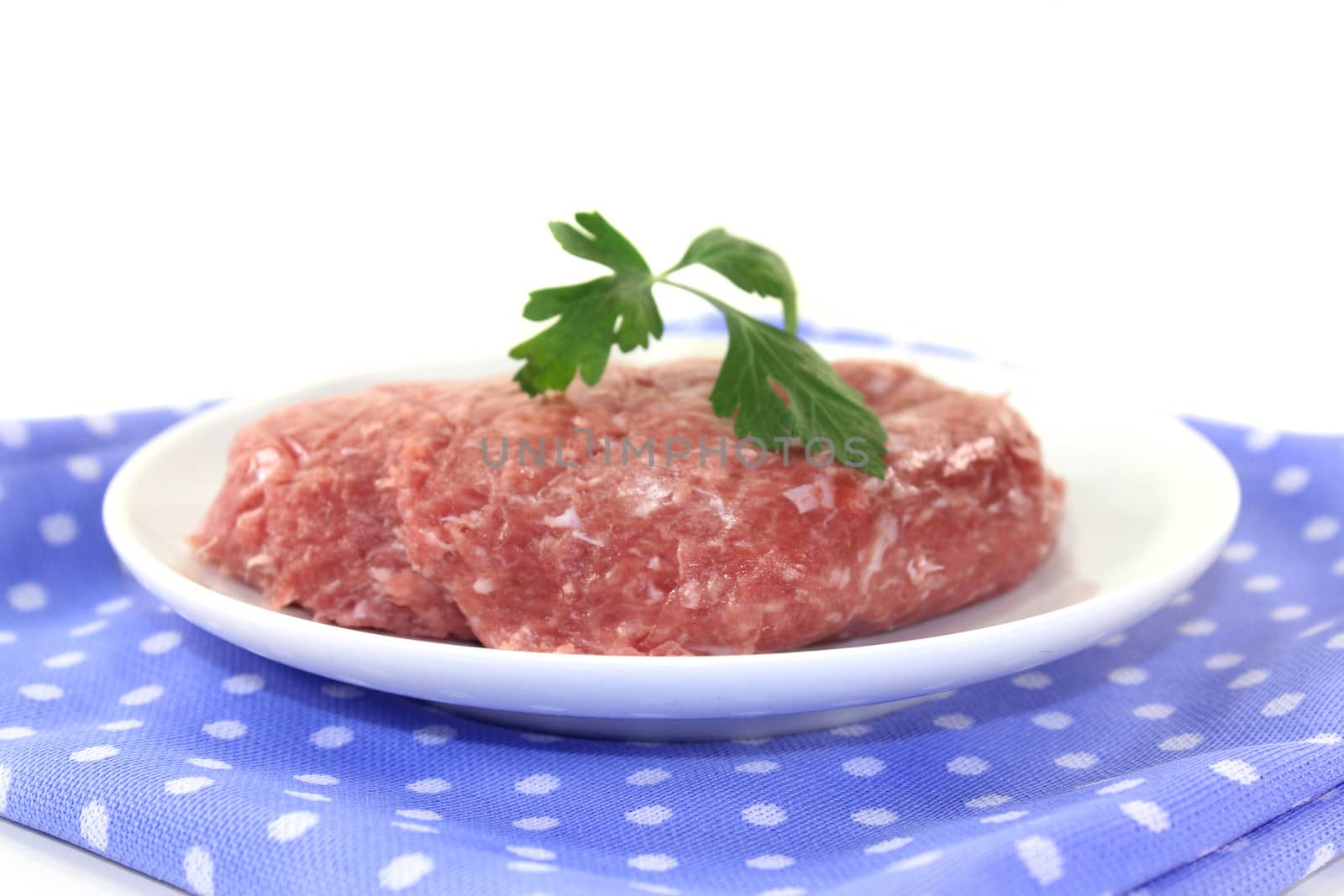 raw minced meat and parsley on a white plate