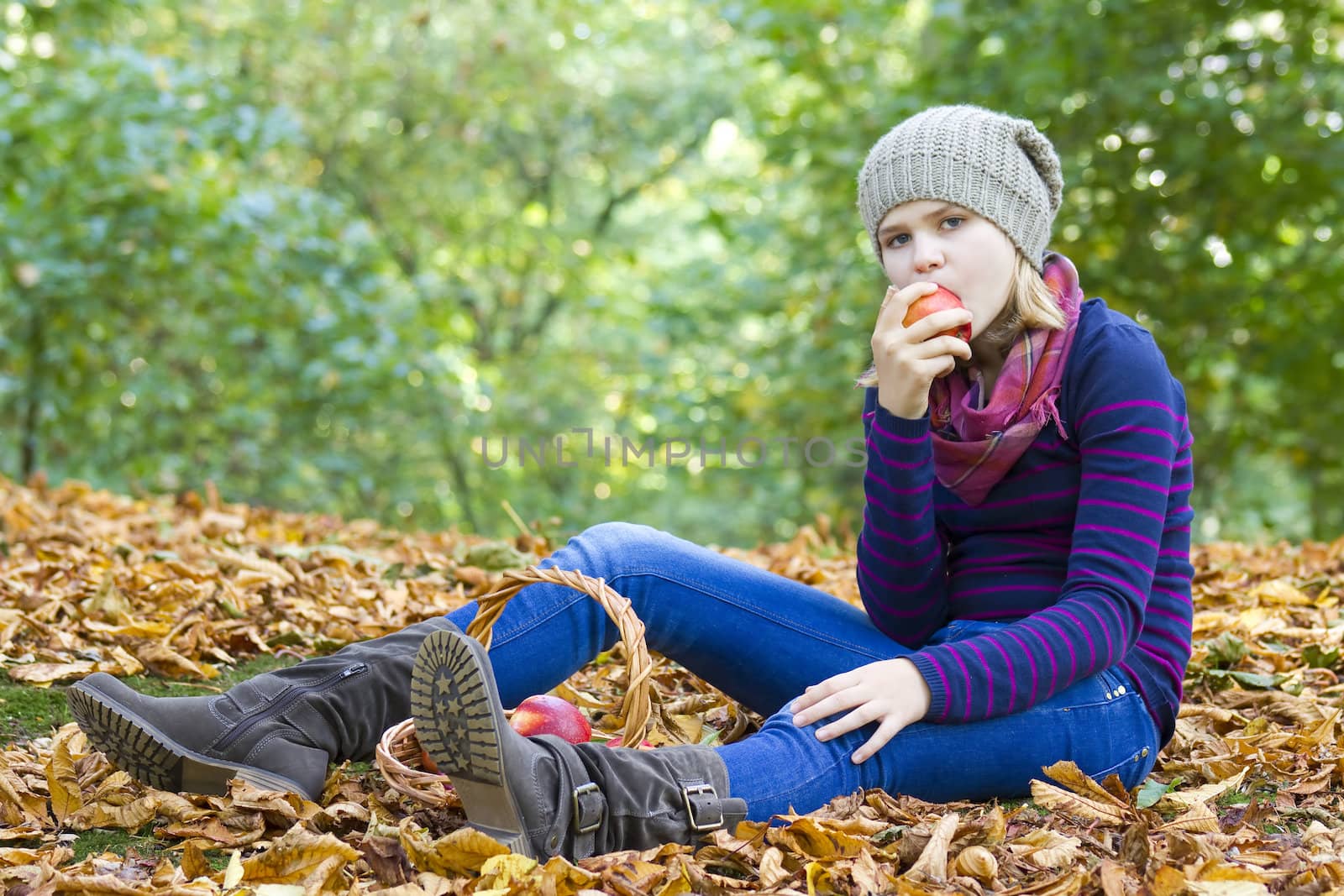 young girl eating red apple in autumn garden
