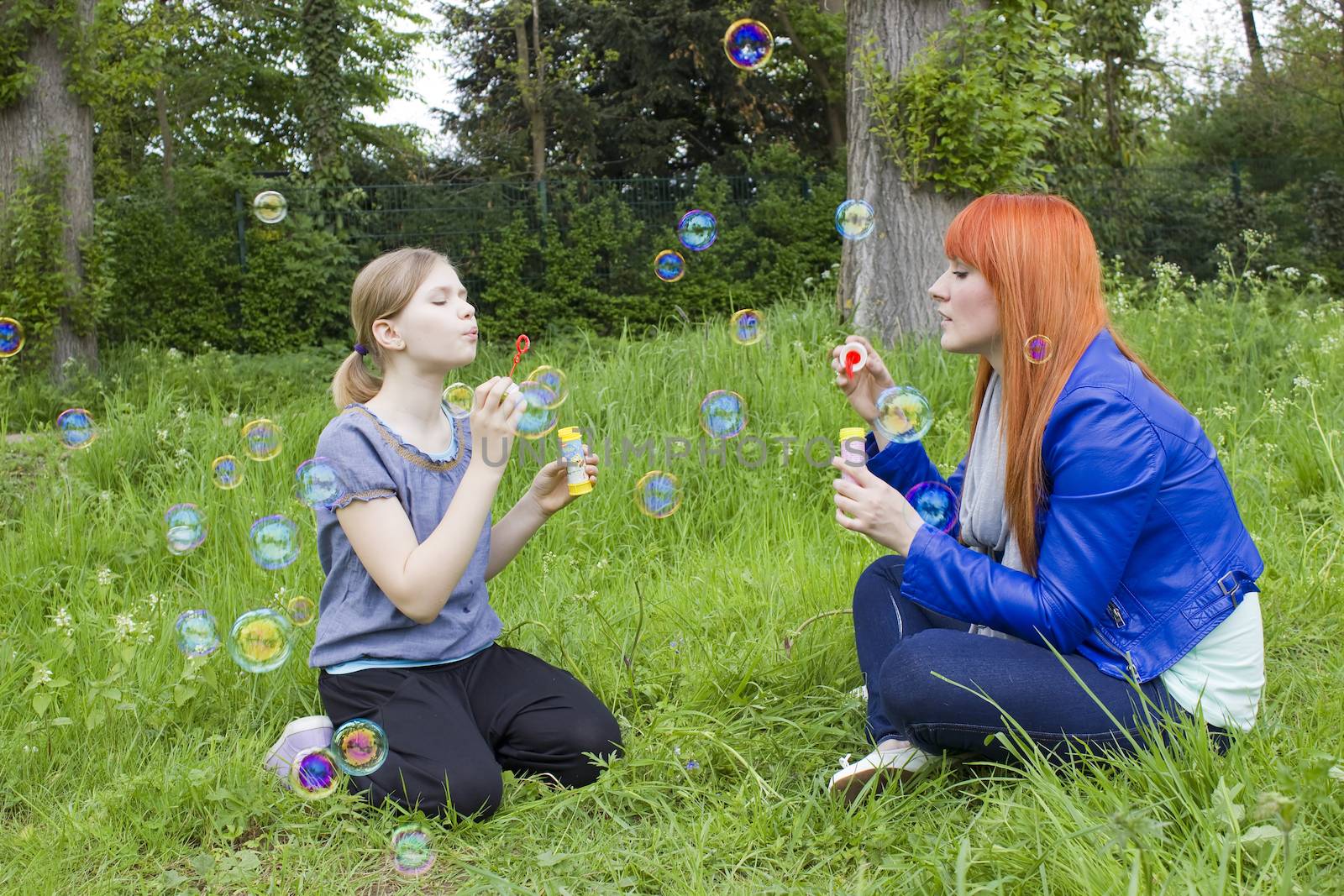 Little girl and young woman blowing soap bubbles by miradrozdowski