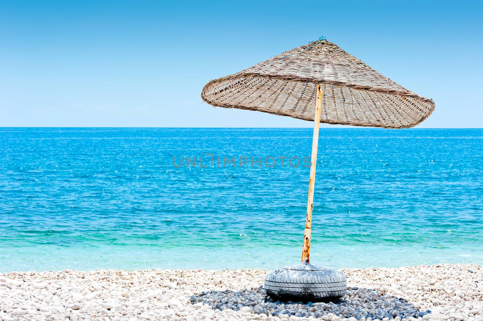 lone wicker umbrella on the beach by kosmsos111