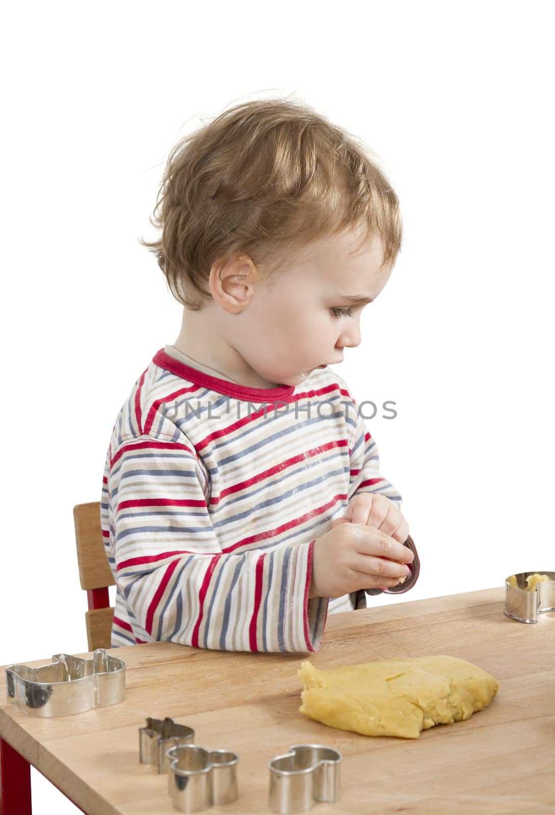 young child with dough sitting on desk. vertical image isolated on white background