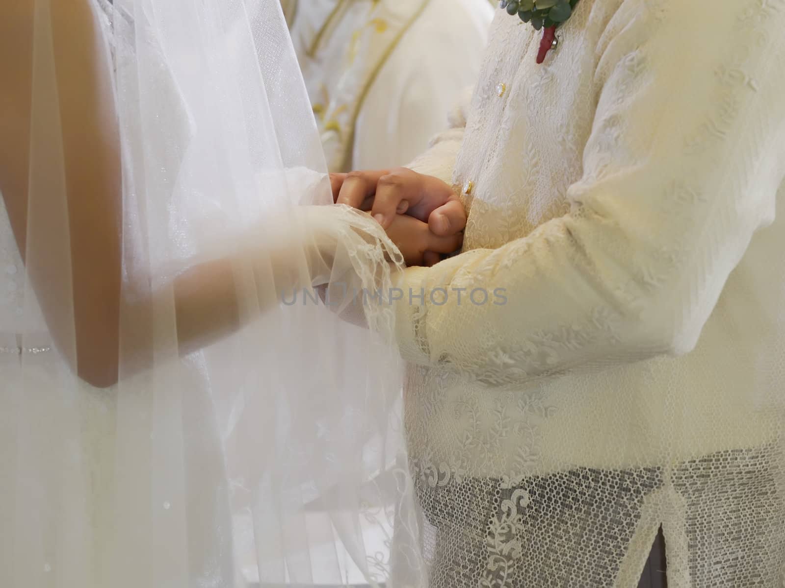 Closeup of bride and groom holding hands during a wedding ceremony