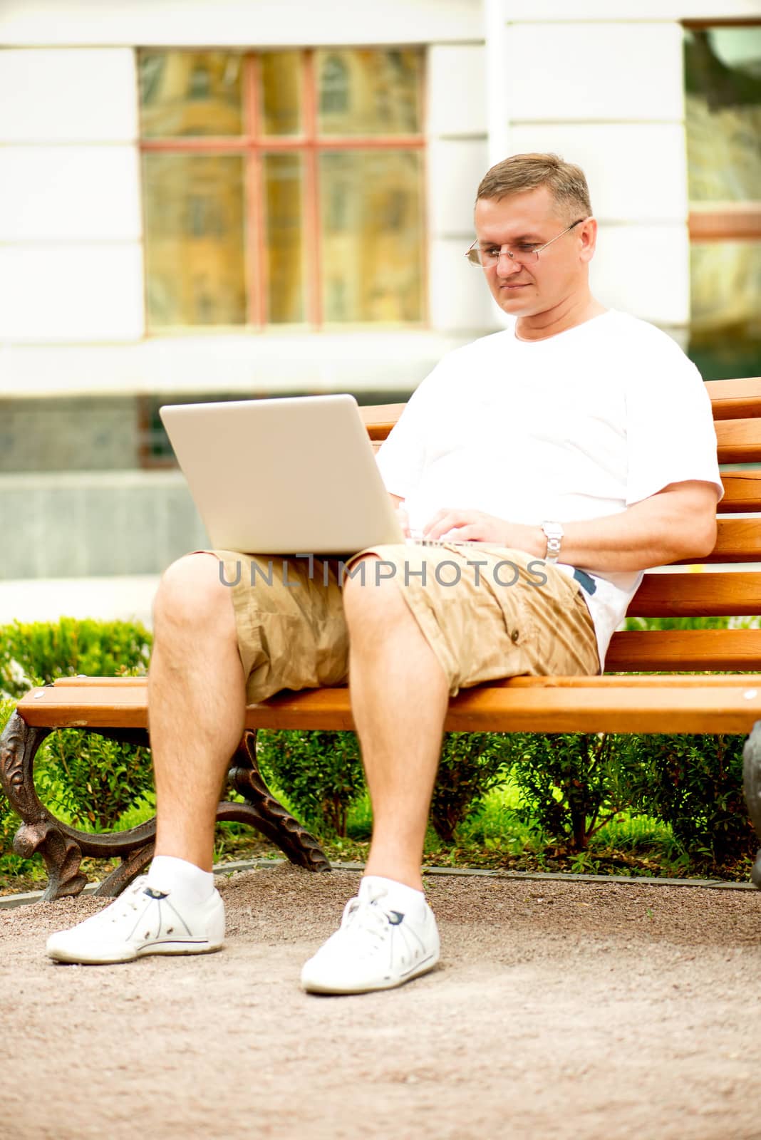 Portrait of a man with laptop sitting on bench