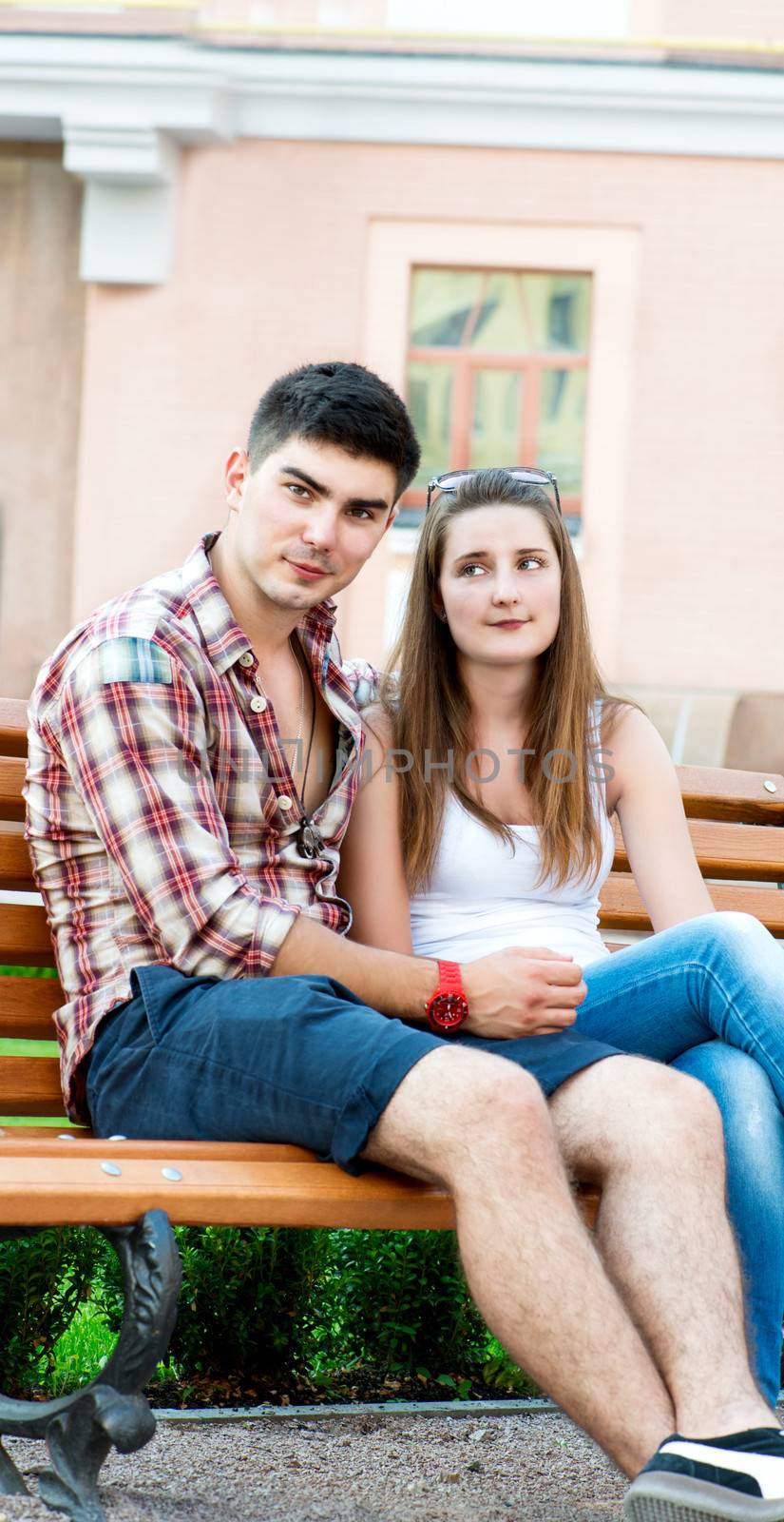 Young couple sitting on bench on street by Nanisimova