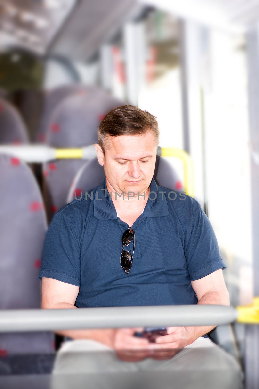 Man traveling on bus and using his smartphone by Nanisimova