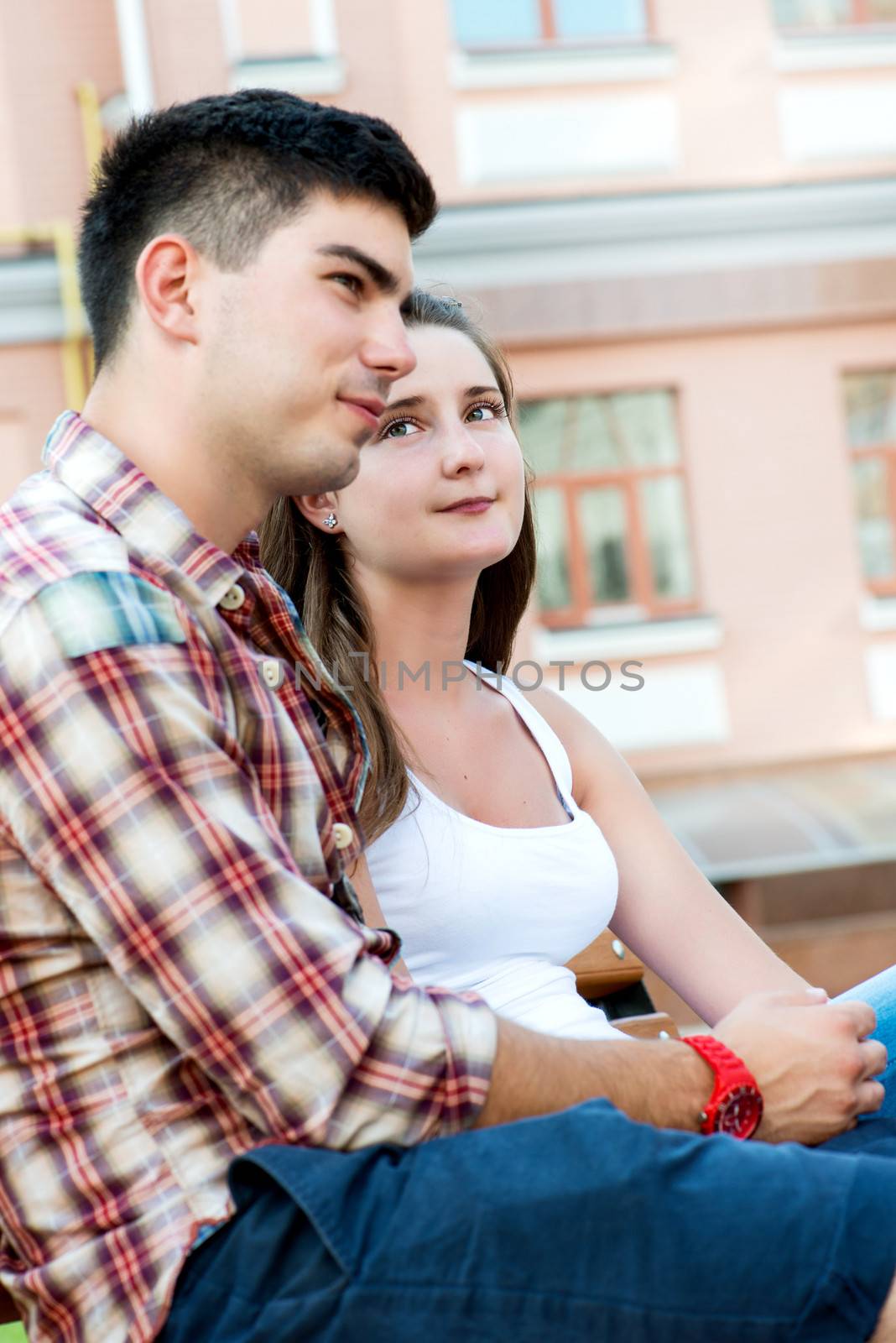 Young couple sitting on bench on street. Side view
