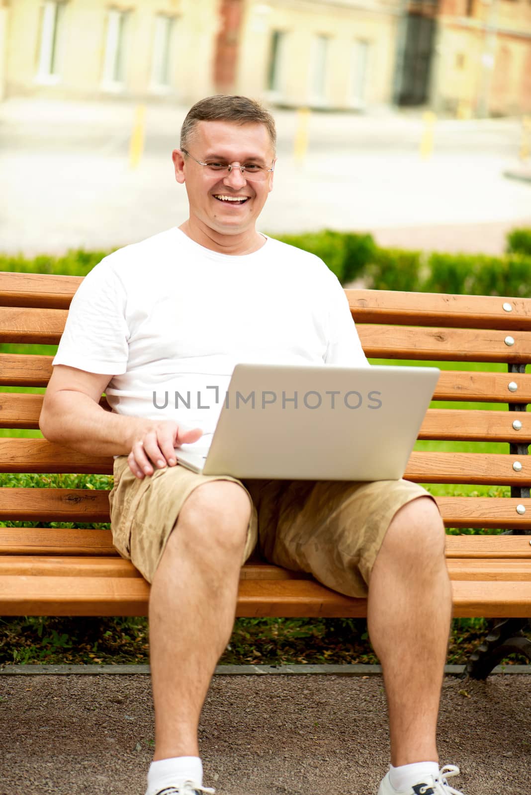 Man with laptop sitting on bench by Nanisimova