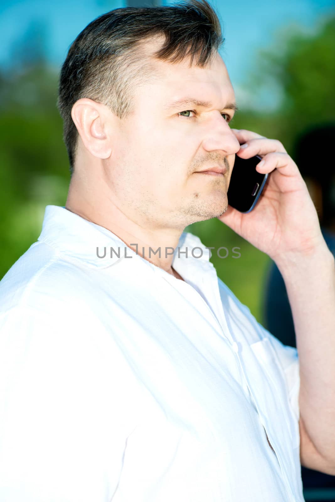 Portrait of middle-aged man with smartphone outdoors by Nanisimova