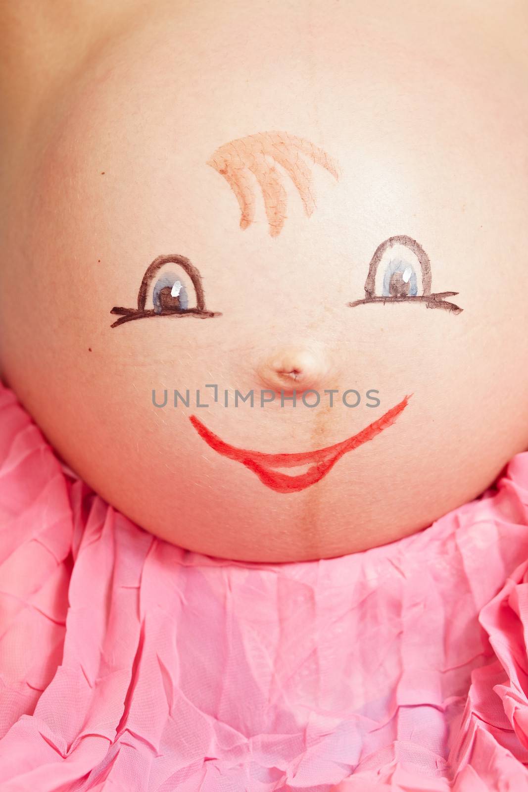 Drawing faces on the belly of pregnant woman