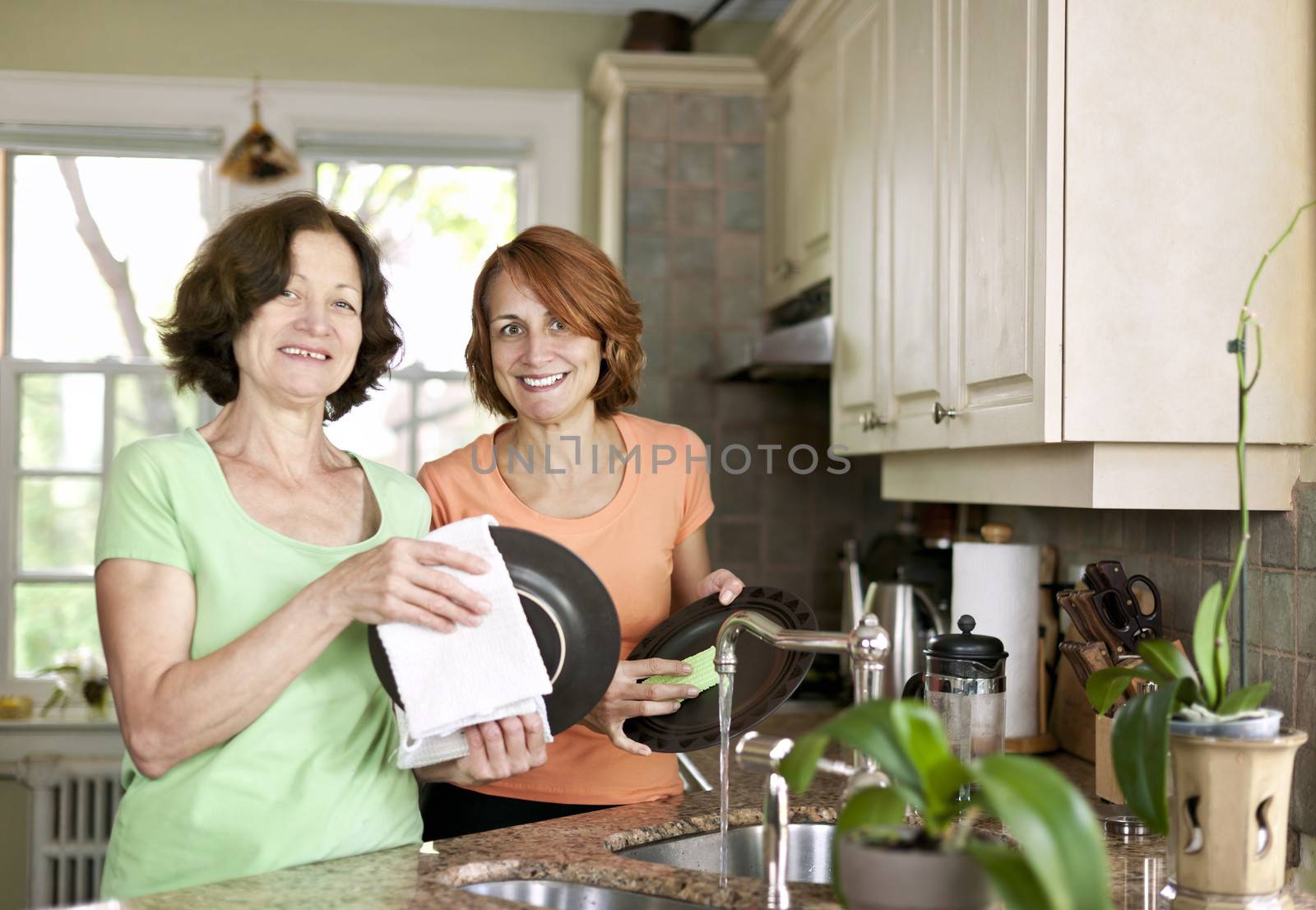 Women doing dishes in kitchen by elenathewise