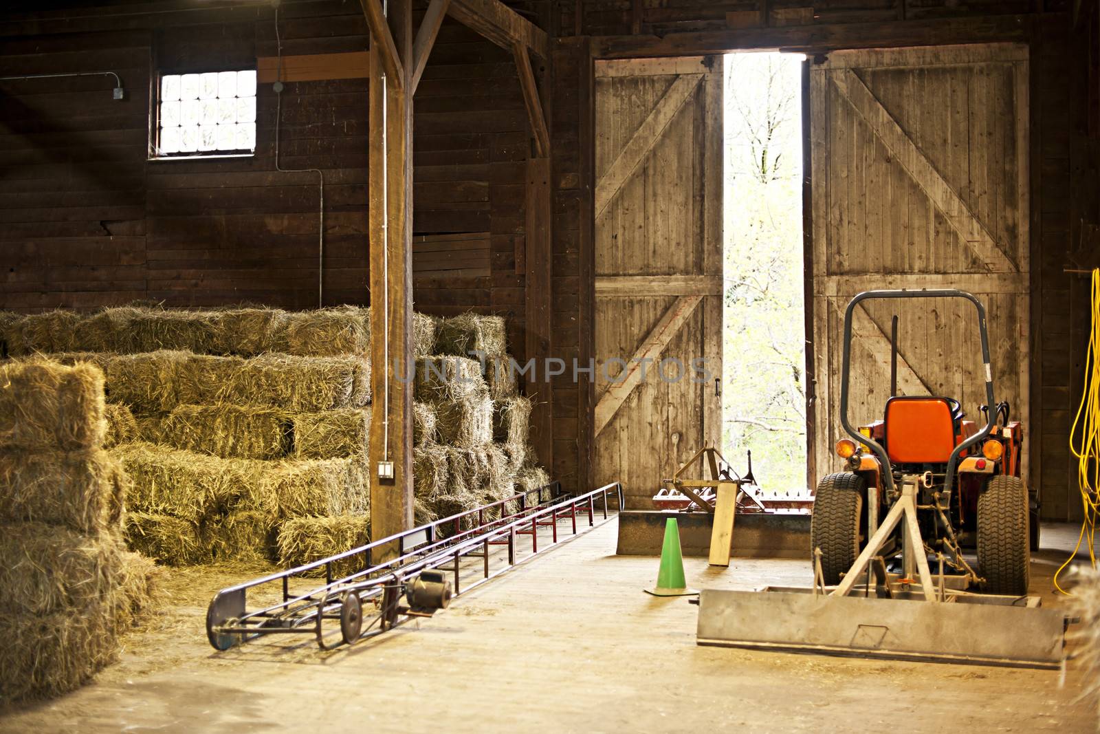 Barn interior with hay bales and farm equipment by elenathewise
