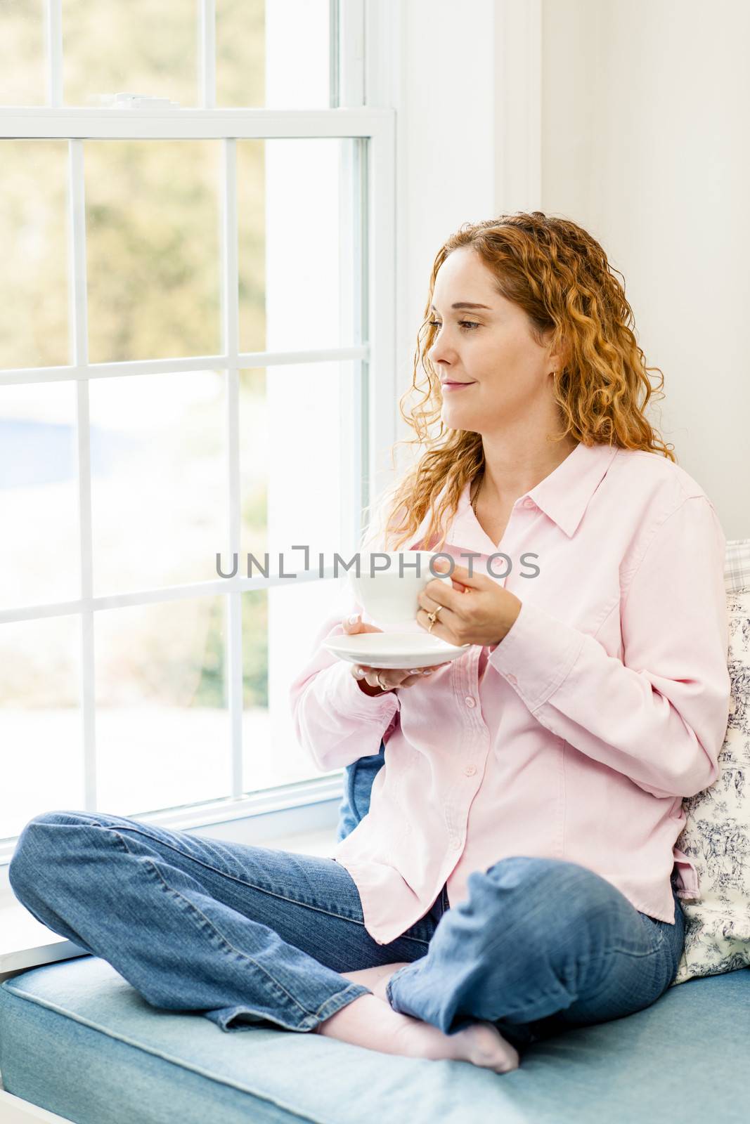 Woman relaxing by the window with coffee by elenathewise
