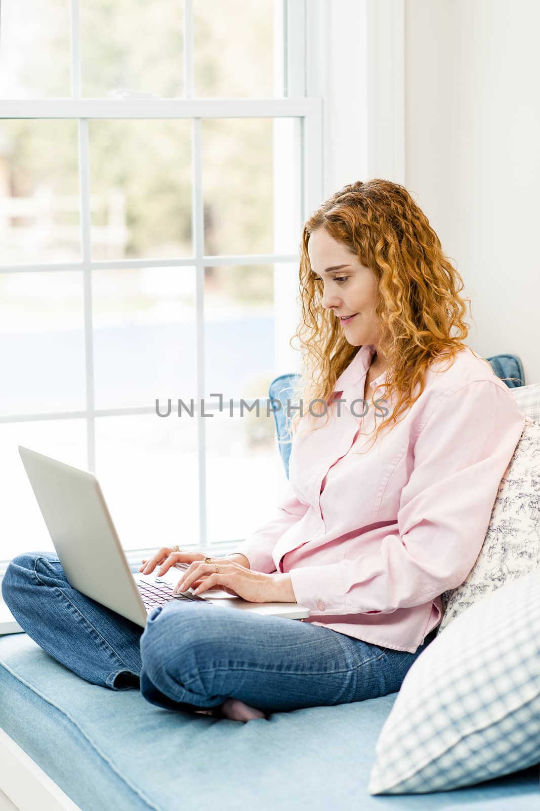 Woman using laptop computer at home by elenathewise