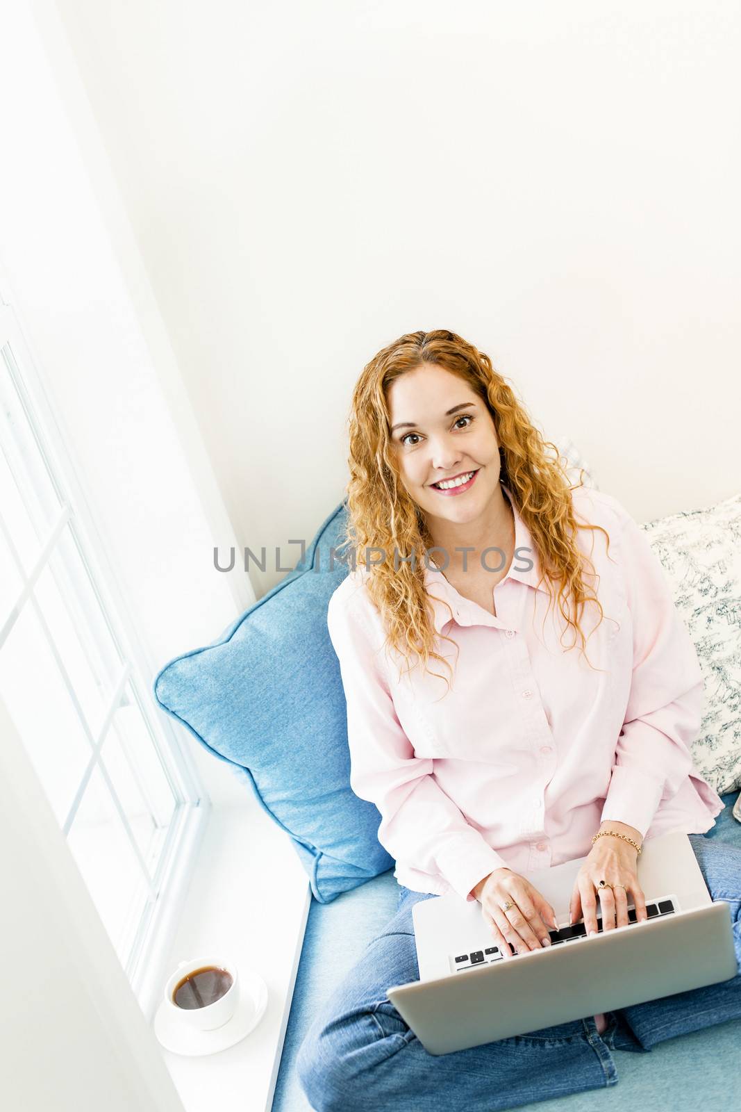 Caucasian woman with laptop computer looking up sitting on couch at home