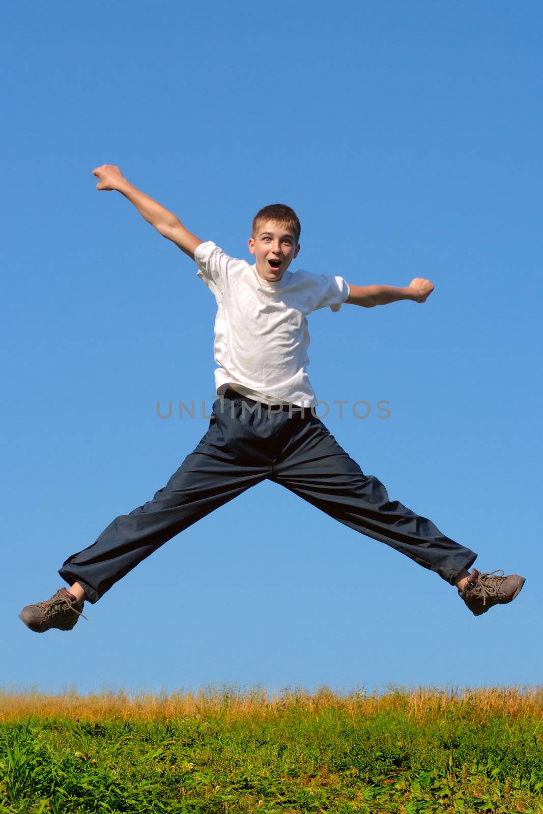 Happy and winning boy jumping on the blue sky background