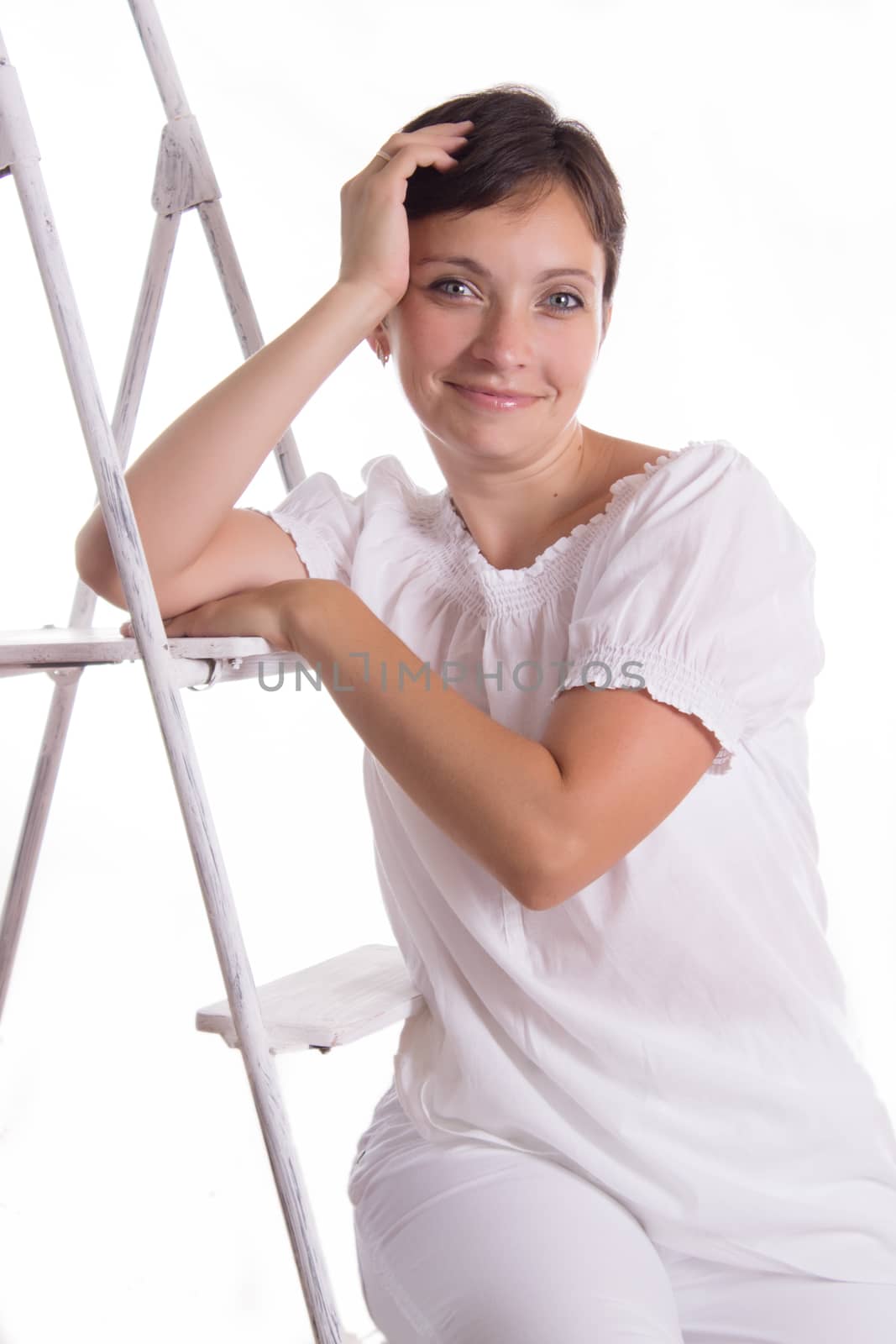 Smiling woman sitting on step ladder isolated on white