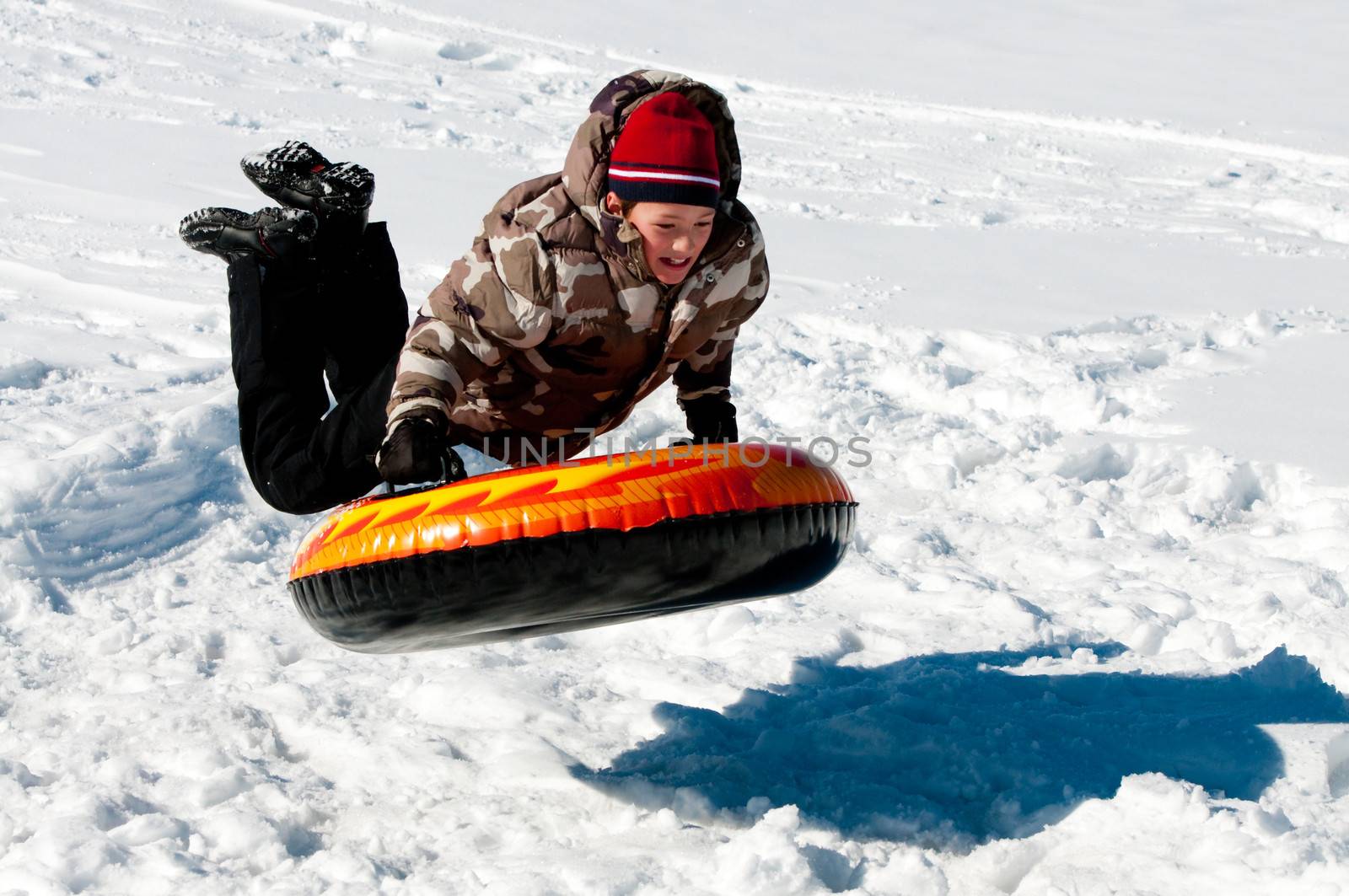 Boy jumping in the air on a tube in the snow