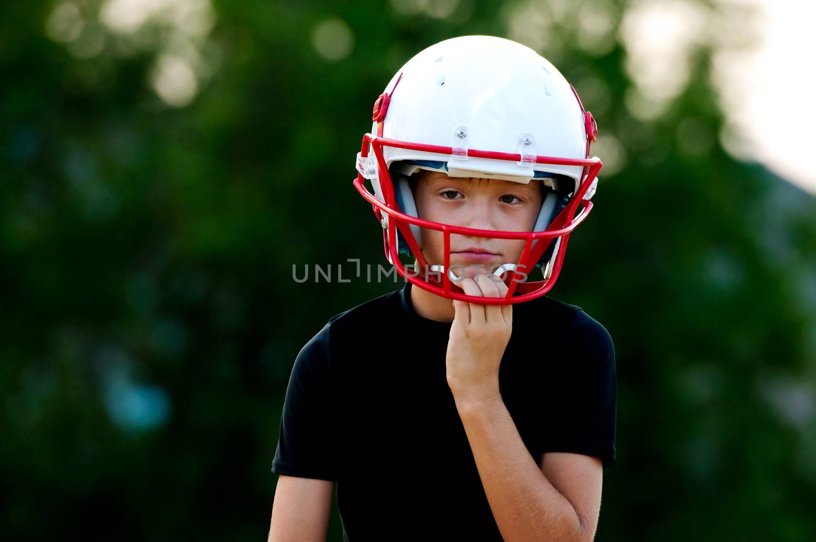 Young football boy in helmet with sad look on face.