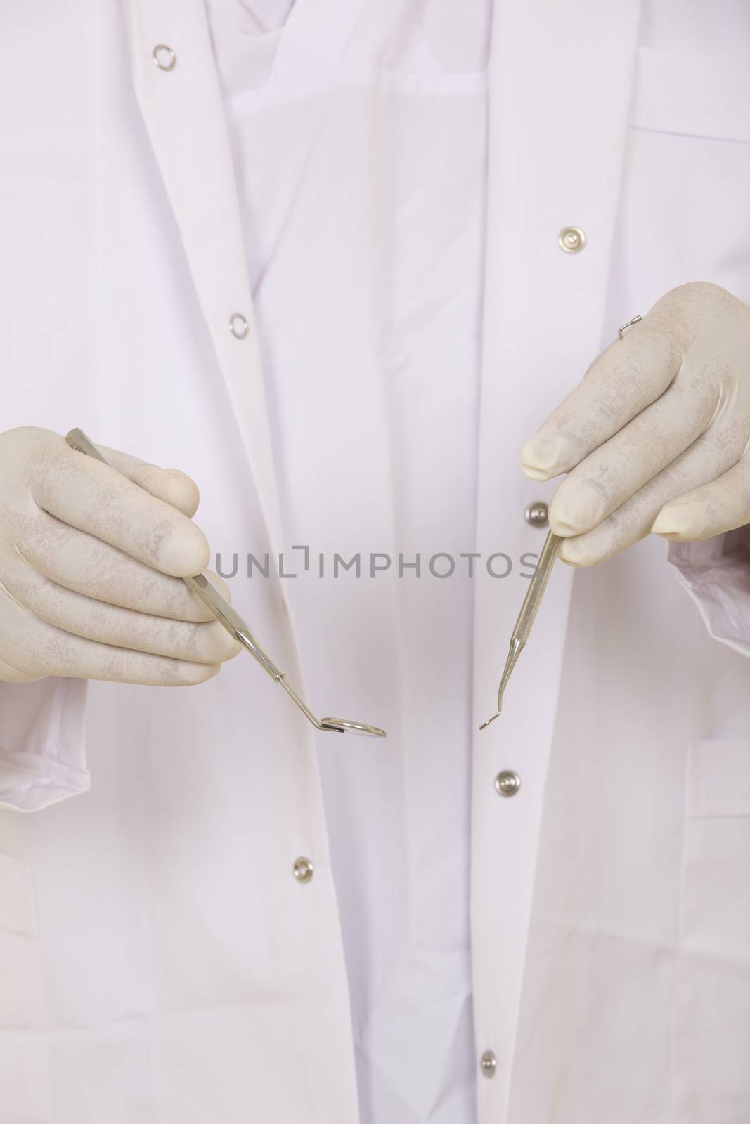 A dentists hands in white medical gloves with dental tools