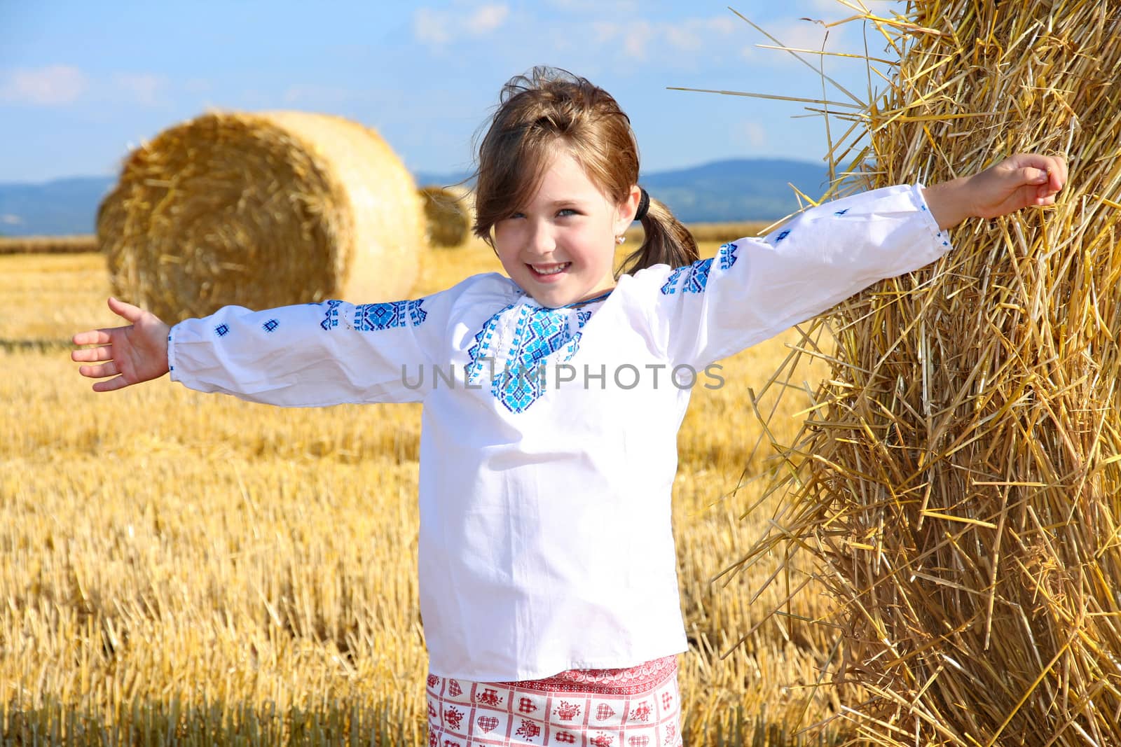 small rural girl on harvest field with straw bales by vladacanon