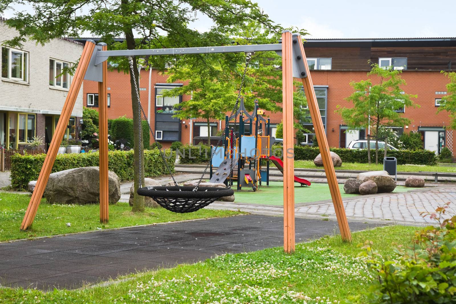 Public playground in modern suburb with colorful wooden climbing construction, swing, slides and rubber floor for safe playing