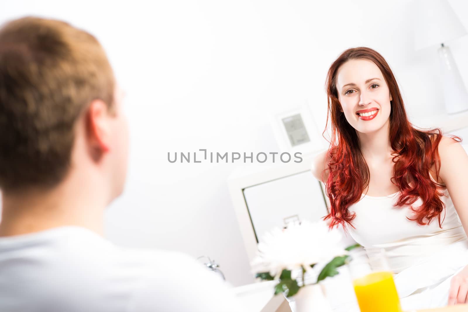 man brought his girlfriend breakfast in bed, holding a tray of juice and breakfast