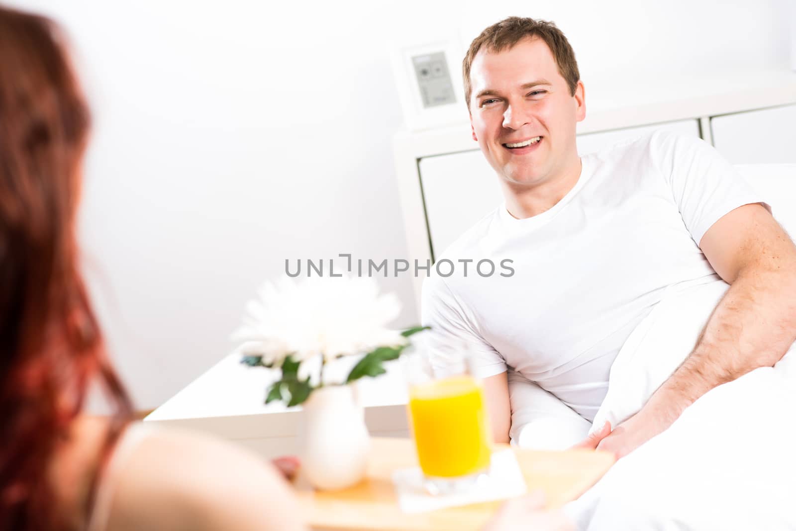 woman brought her boyfriend breakfast in bed, holding a tray of juice and breakfast