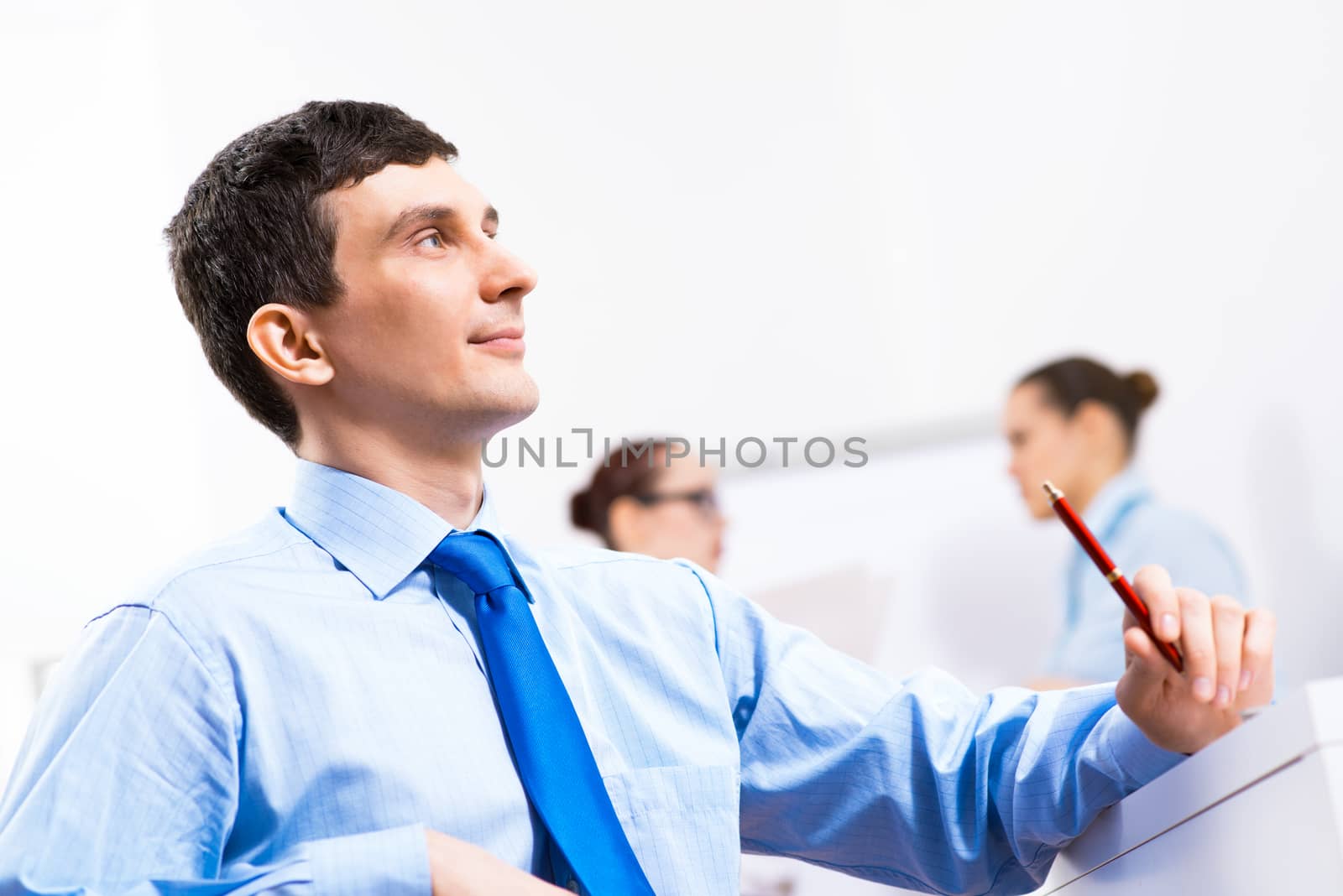 Portrait of a businessman in a blue shirt in the background of colleagues discussing