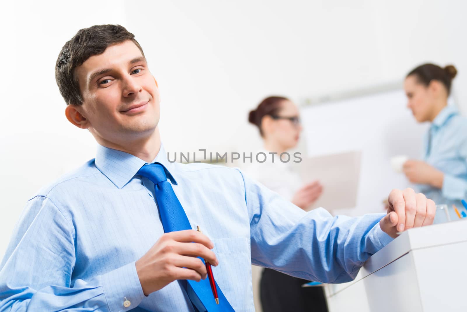 Portrait of a businessman in a blue shirt in the background of colleagues discussing