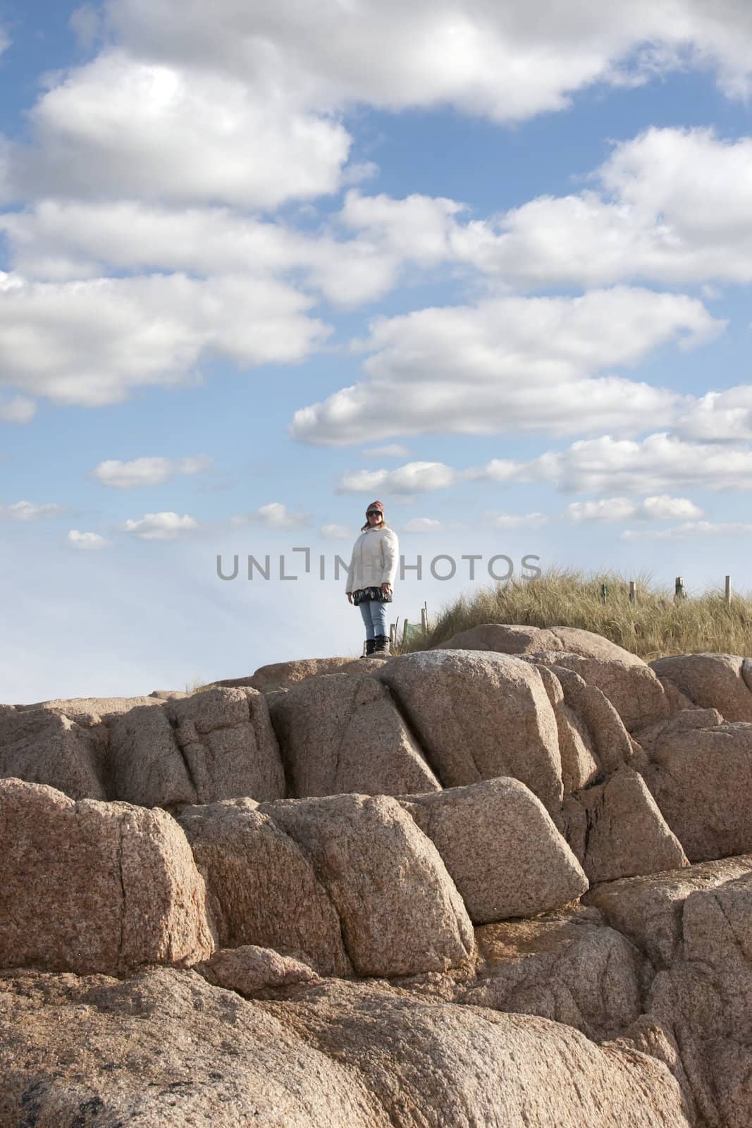woman looking out to sea a top of old rock formation by morrbyte
