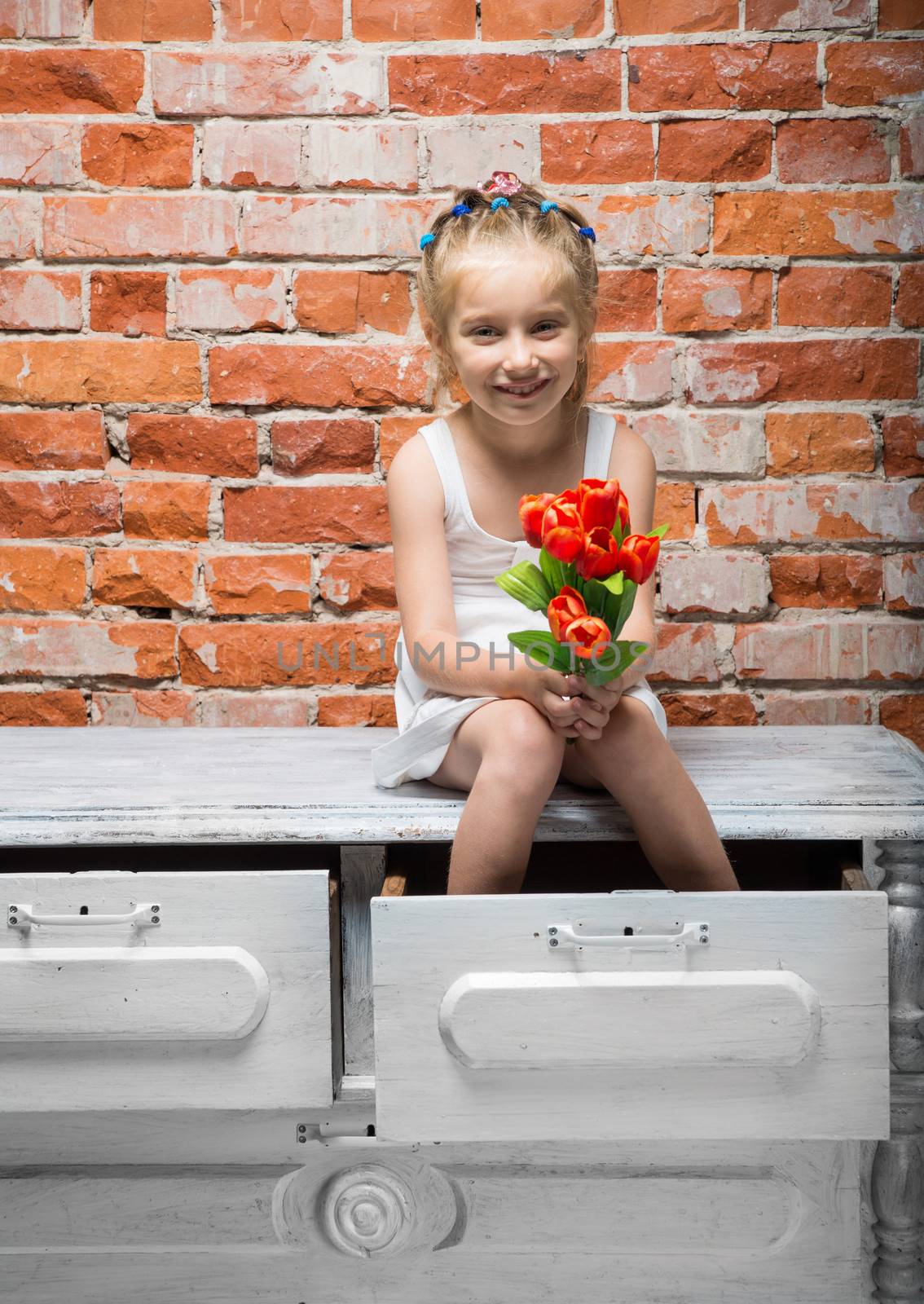 little girl with a bouquet of flowers sitting on the dresser