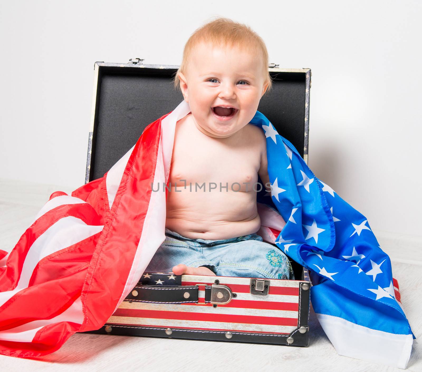 smiling cute baby in a suitcase with American flag