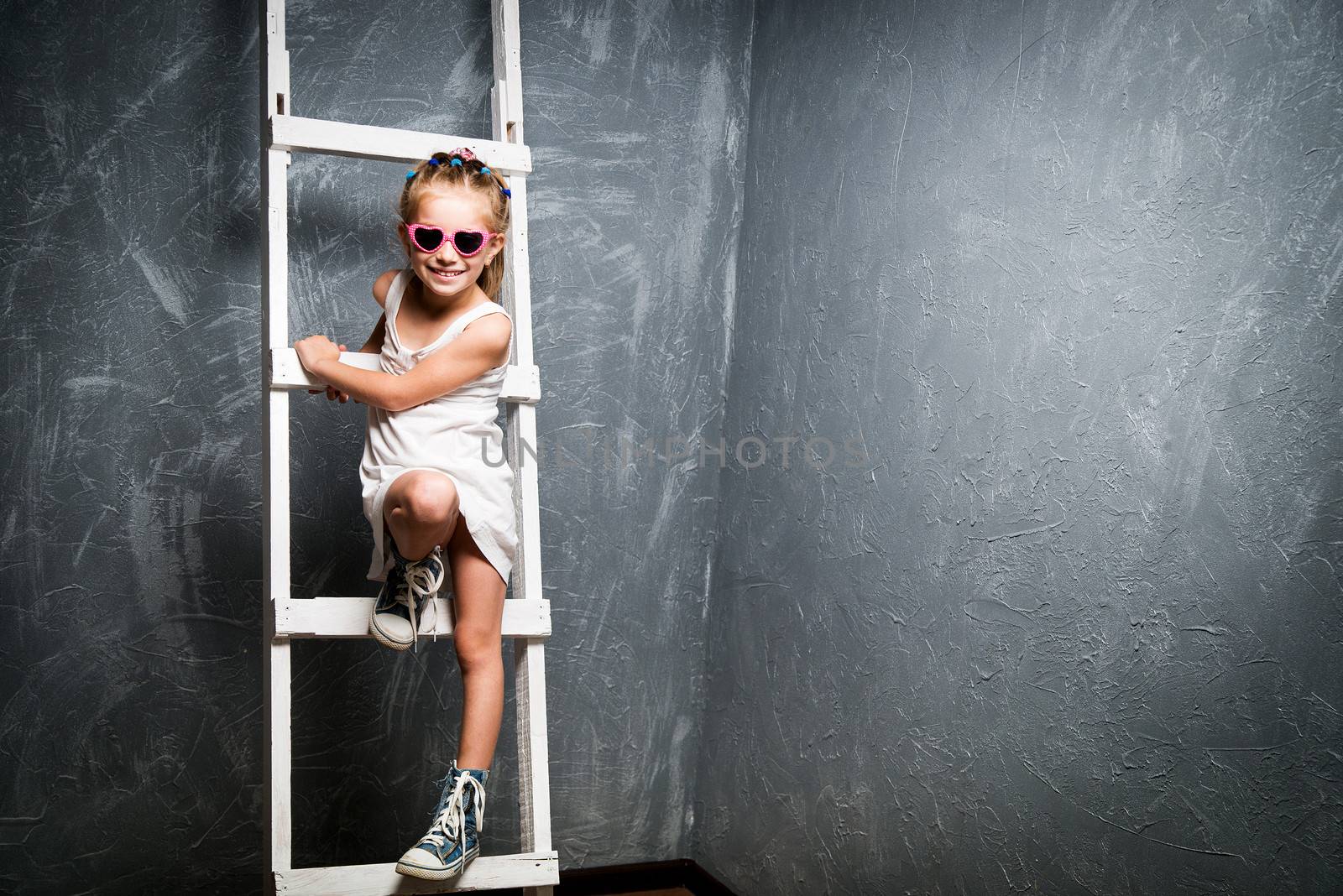 little girl in sunglasses on the white stairs